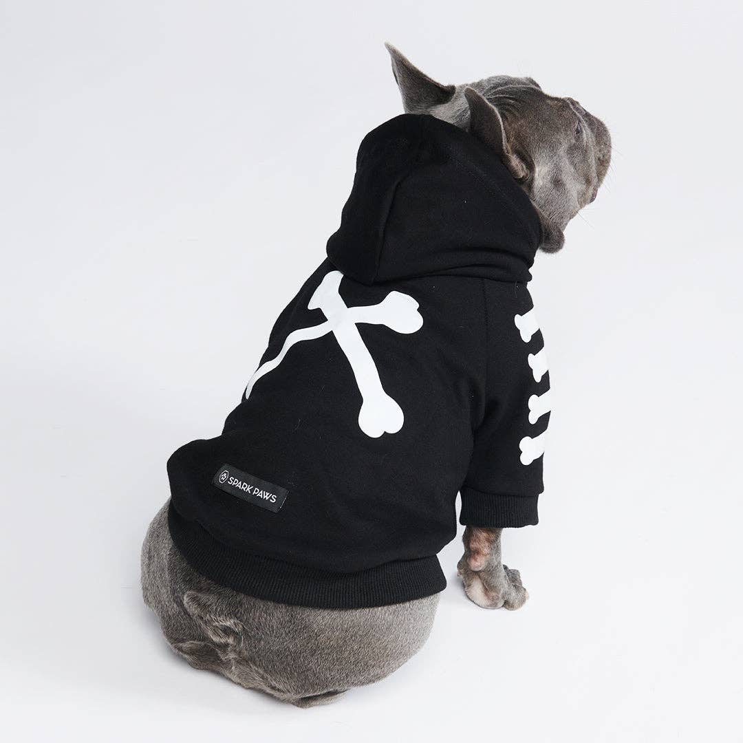 Dog wearing a black hoodie with a white bone design on a white background