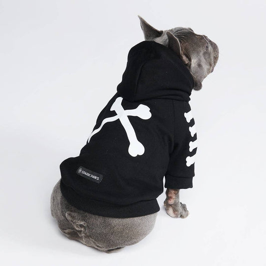 Dog wearing a black hoodie with a white bone design on a white background