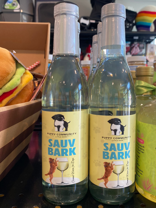 glass bottle of wine with puppy community logo and a golden retriever standing on a glass of wine