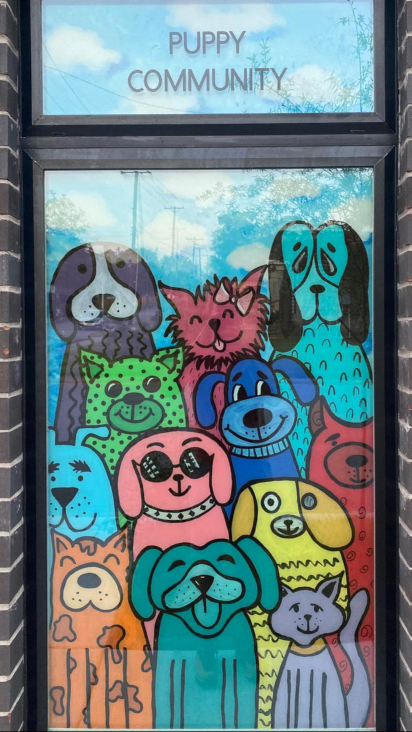 Decorative glass door with colorful dog illustrations and 'Puppy Community' text on a brick wall.