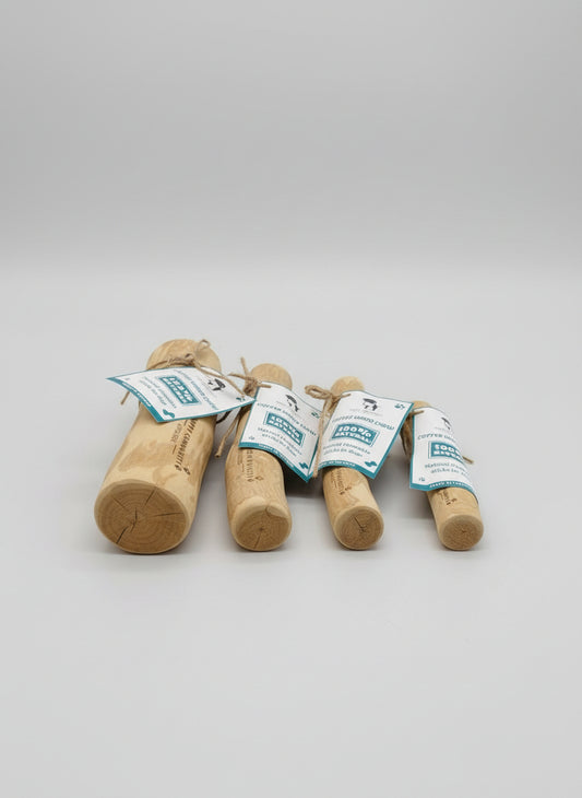 Set of wooden dog chew toys with tags on a dark surface