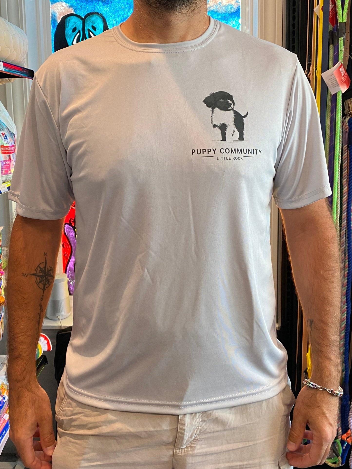 front of a silver tshirt with a puppy community puppy logo on the chest